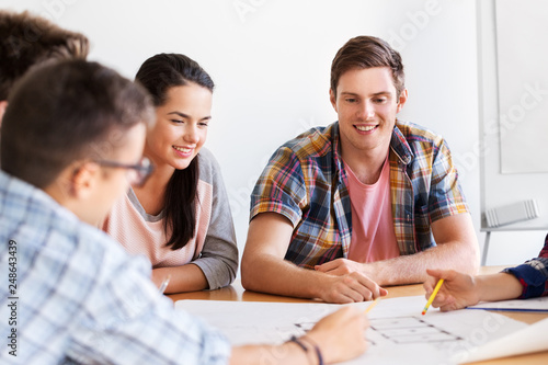 education, architecture and people concept - group of smiling students with blueprint meeting indoors