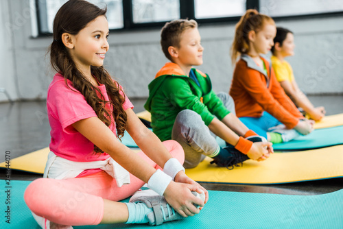 Smiling kids doing gymnastic exercises on fitness mats