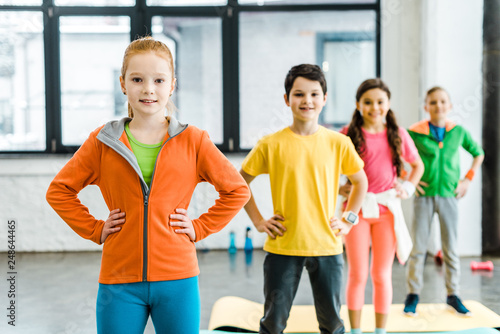 Group of kids standing in gym with arms akimbo