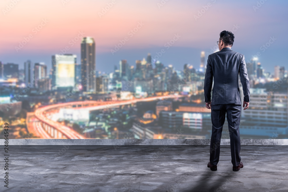 The double exposure image of the business man standing back during sunrise overlay with cityscape image. The concept of modern life, business, city life and internet of things.
