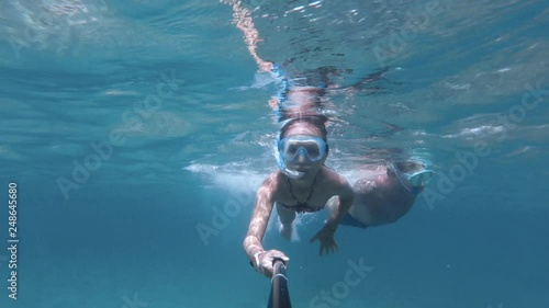 Father and daughter snorkeling in the sea with mask, snorkel and selfie stick, action camera underwater footage