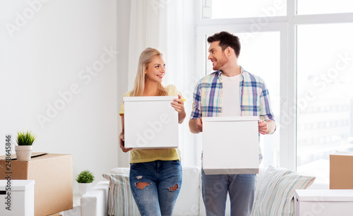 mortgage, people and real estate concept - happy couple with boxes moving to new home