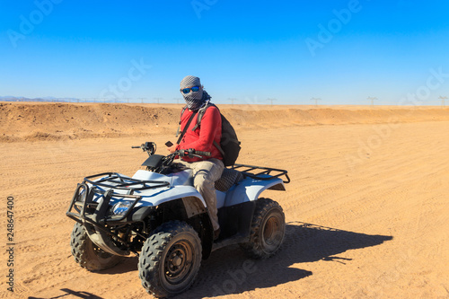 Young man in safari trip through egyptian desert driving ATV. Quad bikes safari in the desert near Hurghada, Egypt © olyasolodenko