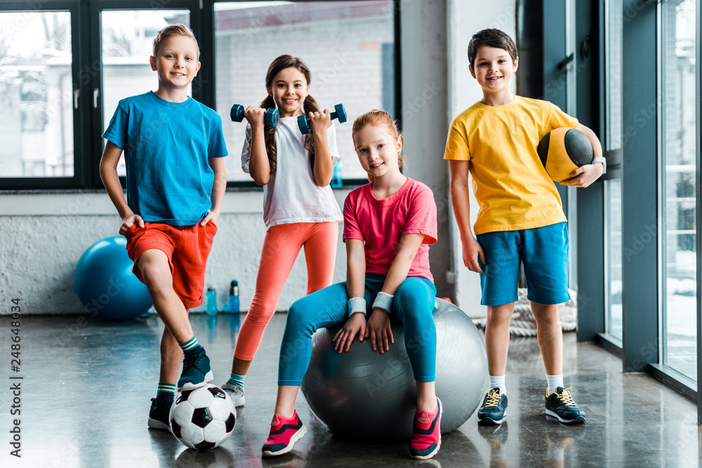 Laughing preteen kids posing with sport equipment - obrazy, fototapety, plakaty 