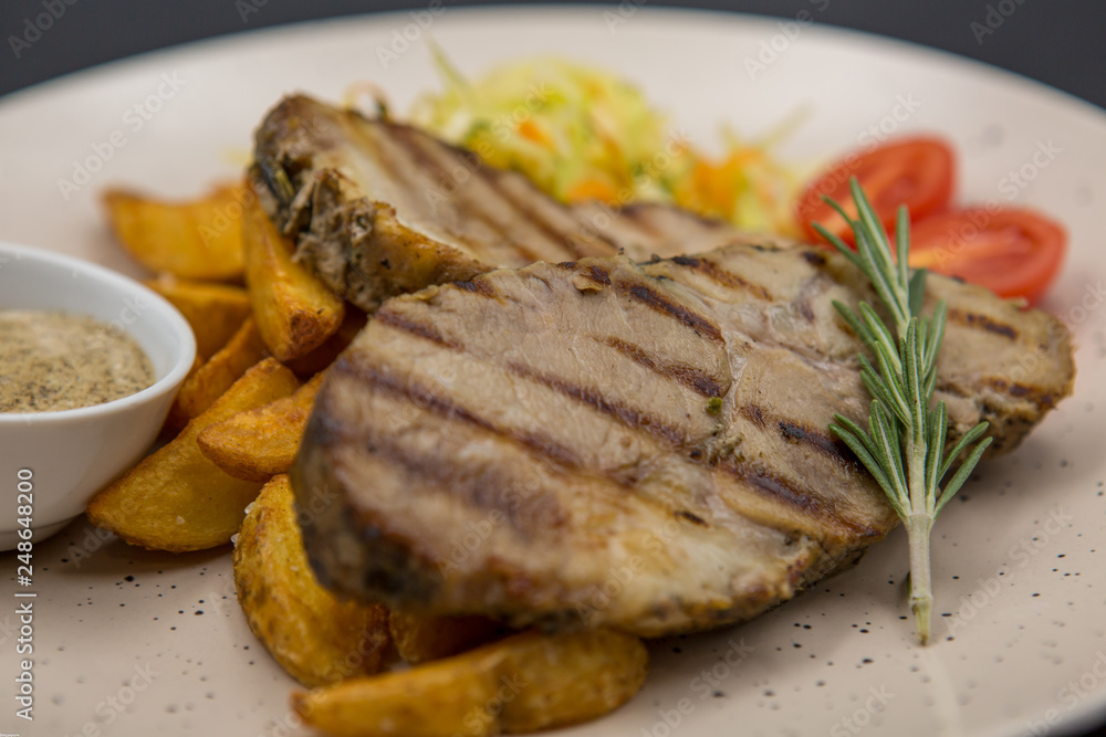A dish of fried pieces of meat with potatoes, tomatoes and specialties on a light plate