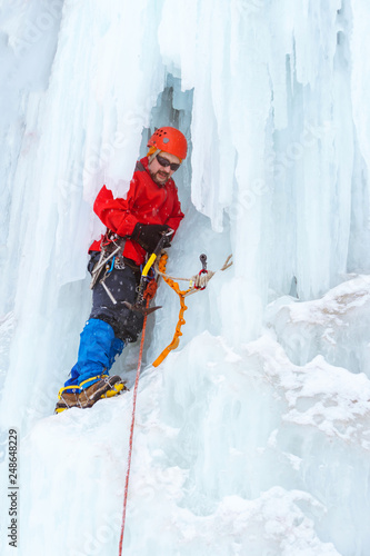 ice climber on the vertical wall of the glacier