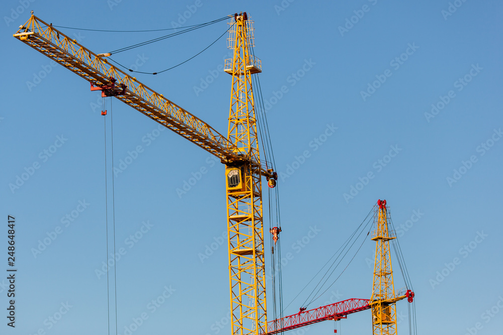 The yellow crane in the daylight. Construction technology. Modern construction crane for lifting building materials