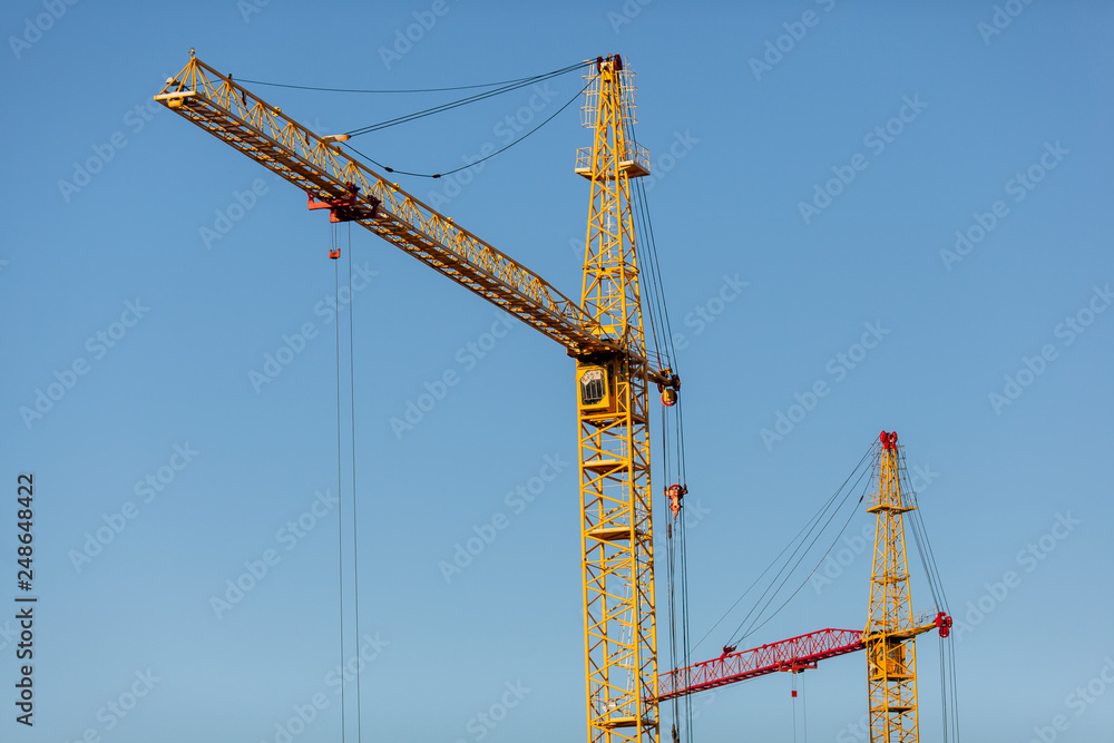 The yellow crane in the daylight. Construction technology. Modern construction crane for lifting building materials