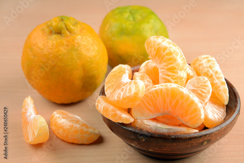tangerines or orange fruit slices in a bowl on wooden table