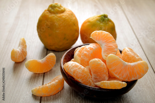 tangerines or orange fruit slices in a bowl on wooden table