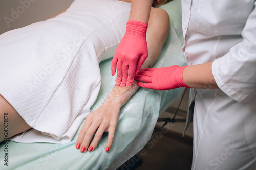 Beautician removes hair from a woman's hand. Sugaring. Hair removal with a special sugar paste has many advantages over wax depilation.. © Semachkovsky 