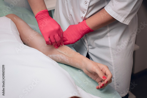 Beautician removes hair from a woman's hand. Sugaring. Hair removal with a special sugar paste has many advantages over wax depilation..