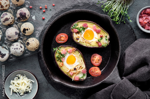 Keto diet dish: Avocado boats with ham cubes, quail eggs, cheese, ingredients around