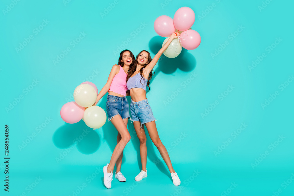 Fototapeta premium Full length body size photo funny beautiful amazing two she her ladies colored balloons hands arms mood beach party wearing shiny jeans denim shorts tank tops isolated teal bright vivid background