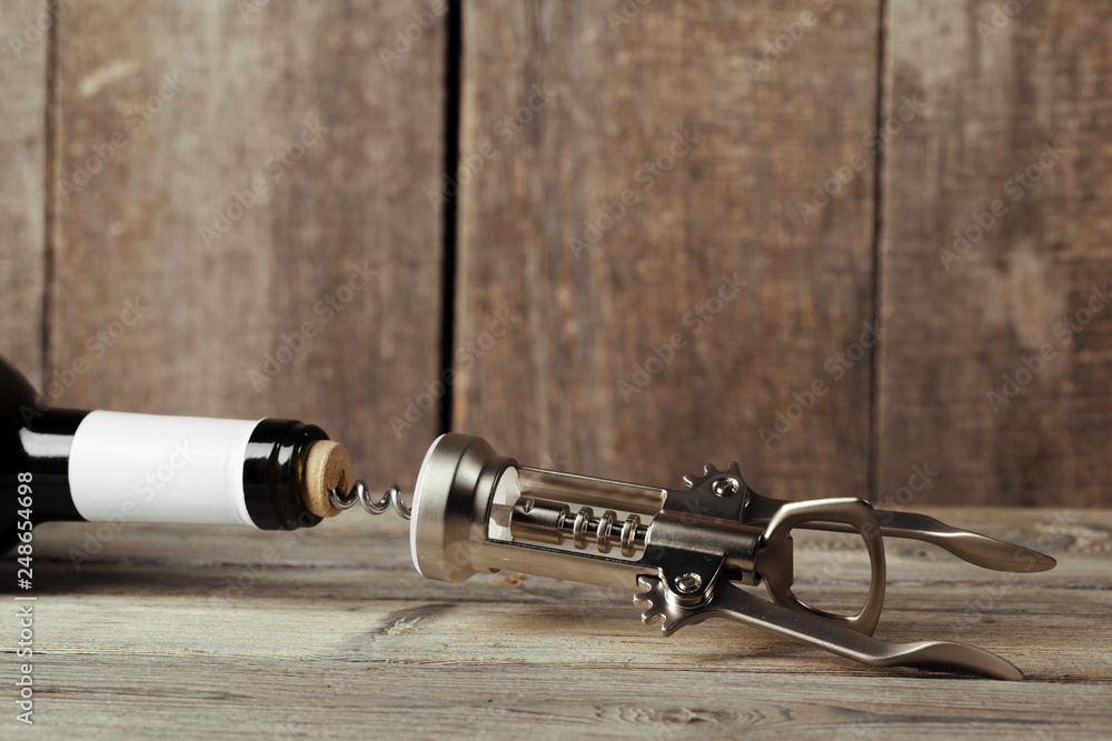 Bottle of wine with corkscrew on wooden background Bottle of wine with corkscrew on wooden background
