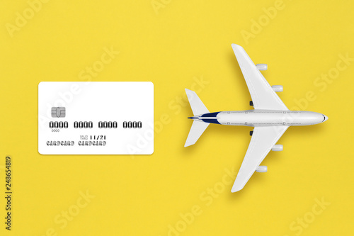 Model of airplane and credit card mock-up on yellow background