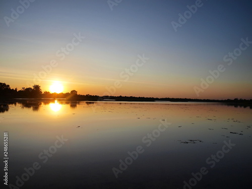 Beautiful sunset over the reservoir and Silhouettes landscape view sunset Water reflection On the background is a black cloud and blue sky. © kanin