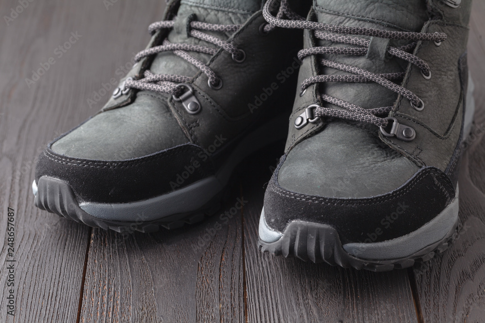 Dark boots with shoelace on wooden background Dark boots with shoelace on wooden background
