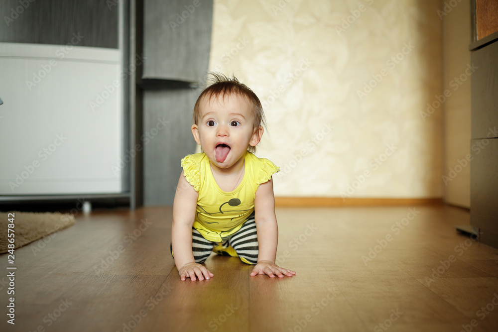 A little girl crawling on the floor with her tongue out in a yellow bee costume A little girl crawling on the floor with her tongue out in a yellow bee costume