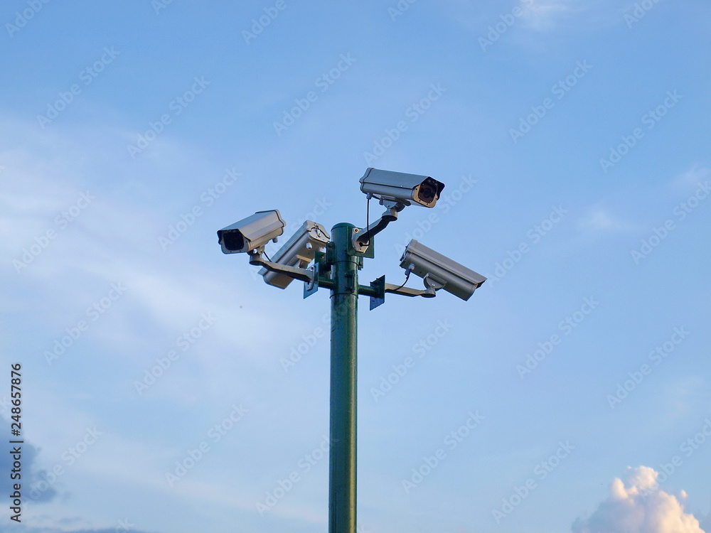 CCTV on green pillars to secure The background is a blue sky with a thin white cloud. CCTV on green pillars to secure The background is a blue sky with a thin white cloud.