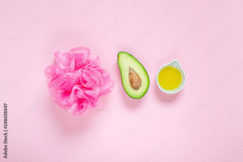 Avocado oil and bathroom accessories on pastel pink background, top view, copy space, SPA concept body care, homemade