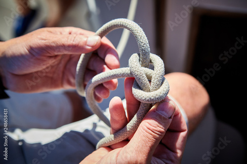 Male hands tying knot on yacht sail boat