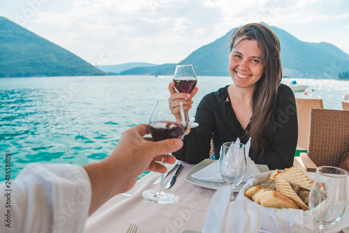 woman with man drinking wine in restaurant at seaside with beautiful view of bay and mountains © phpetrunina14
