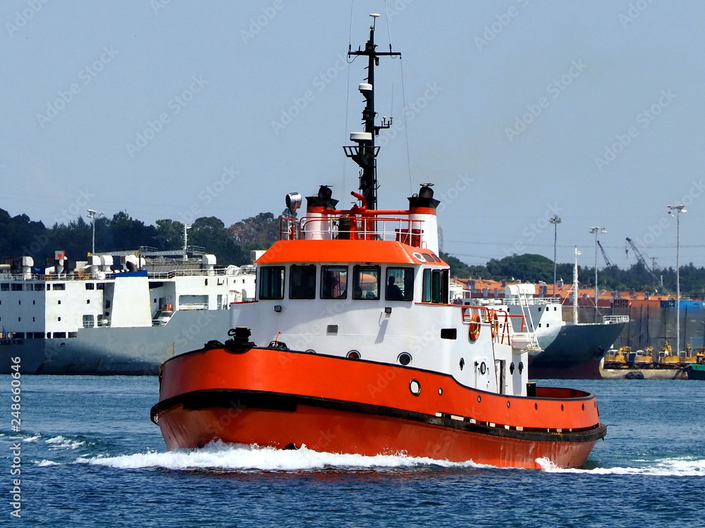 Fototapeta premium Red Tugboat underway in harbour boundries to towing assistance operation.