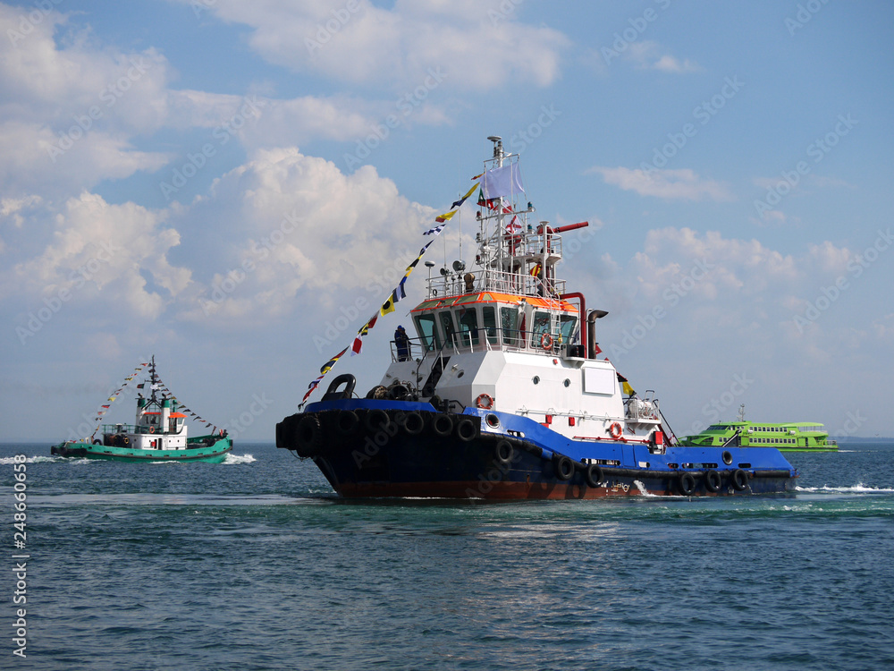 Harbour tugboats maneuvering in bay during maritime festival activities.