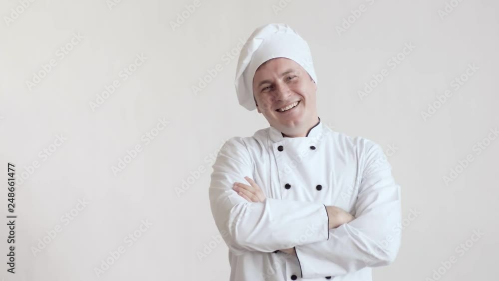 Bright cook man in chef's clothes, waist-deep in a bright room, standing with his hands folded on his chest and showing class and smiling looking at the camera Bright cook man in chef's clothes, waist-deep in a bright room, standing with his hands folded on his chest and showing class and smiling looking at the camera