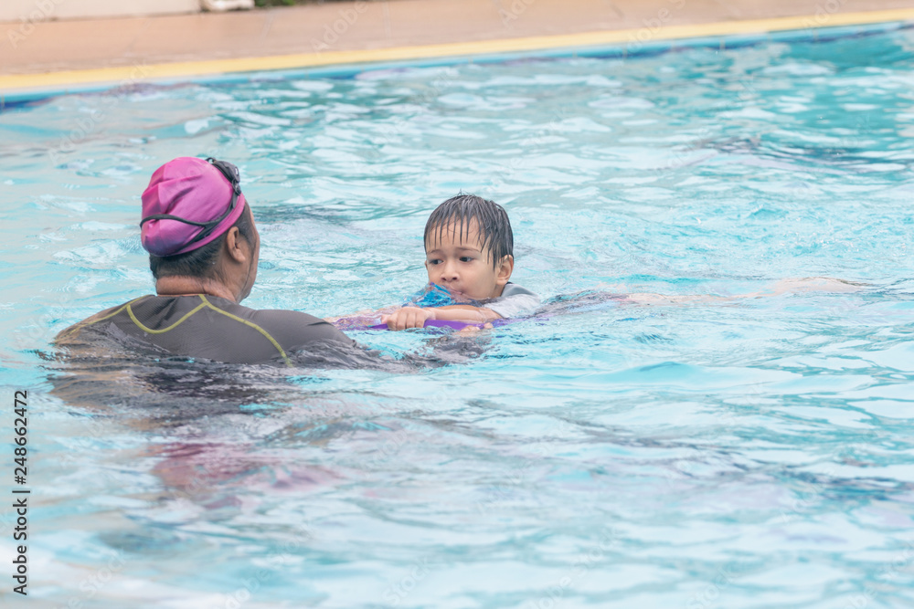 Boy learning to swim with coach.