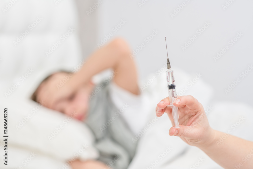 Close up view of a syringe with a child at the background Close up view of a syringe with a child at the background