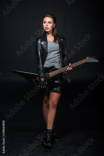 beautiful woman in leather jacket with electric guitar isolated on black
