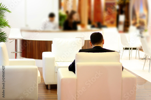 A man waiting on the white couch in the hotel lobby