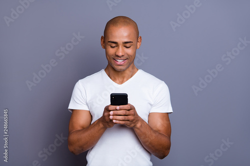 Close up photo strong healthy dark skin he him his macho bald head telephone arms reader foreign pen-friend exciting amazing communication wearing white t-shirt outfit clothes isolated grey background © deagreez