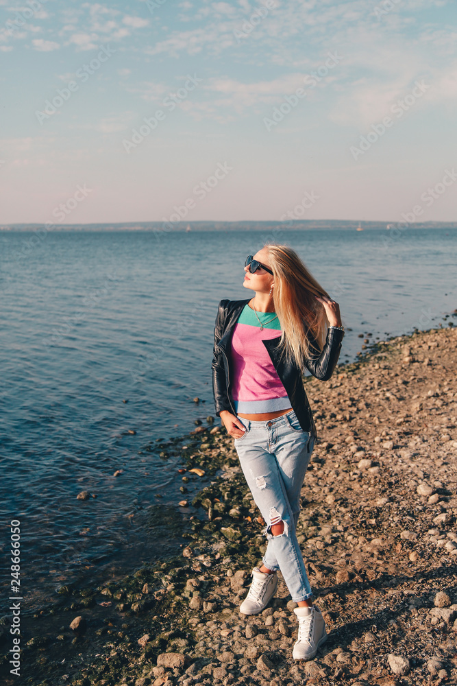 Blonde girl with long hair on a photo shoot by the sea