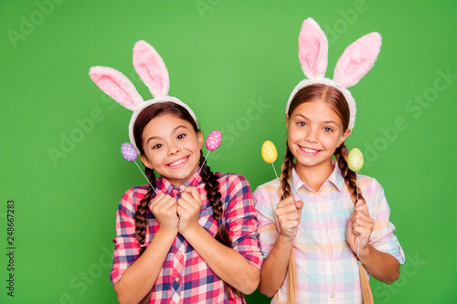 Close up photo of charming with beaming toothy smile white caucasian latin hispanic kids school girls holding colorful eggs in hands isolated bright vivid background
