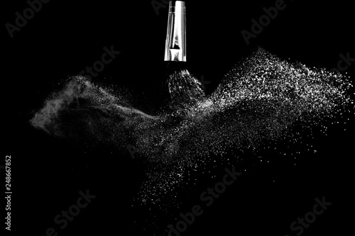 Cosmetic brush with white cosmetic powder spreading for makeup artist or graphic design in black background