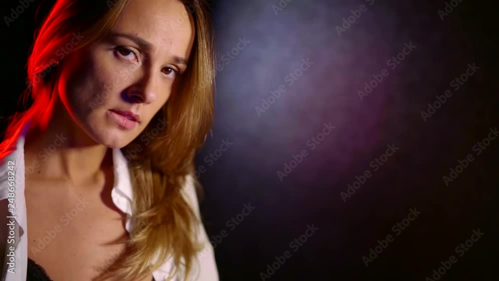 Portrait of a very beautiful blonde woman slightly bitting her lower lip wearing unbuttoned white shirt. Portrait of a very beautiful blonde woman slightly bitting her lower lip wearing unbuttoned white shirt.