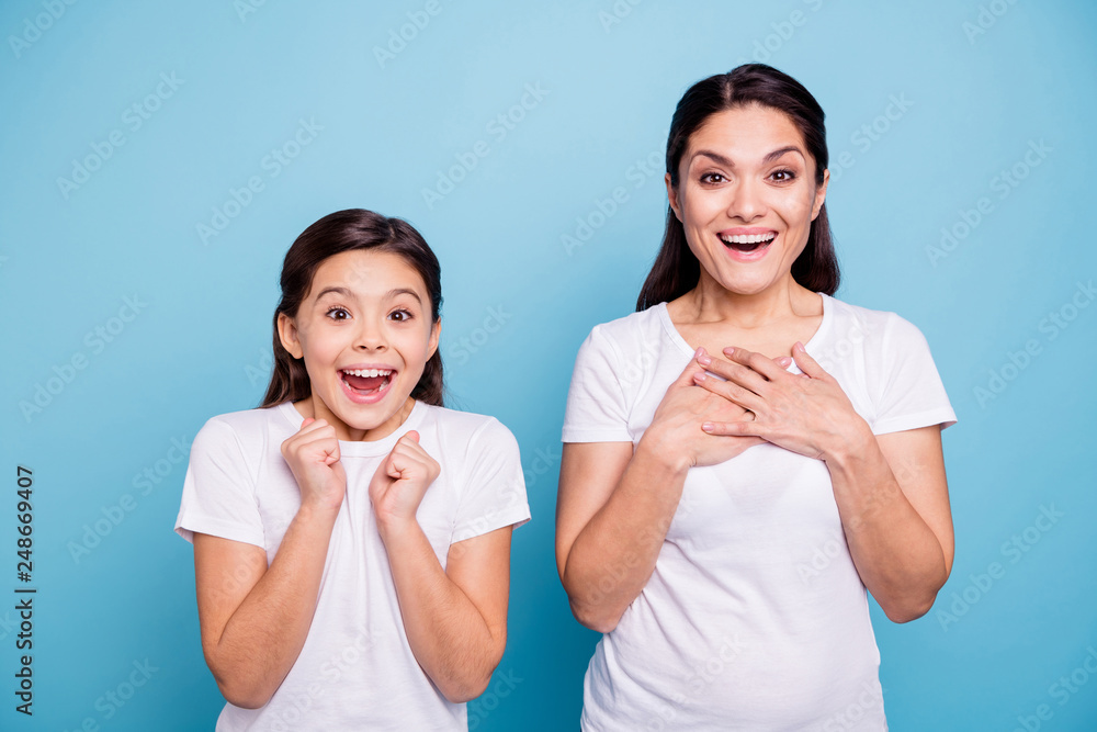 Close up photo pretty two people brown haired mum little daughter eyes mouth opened unbelievable arms point herself win lottery prize wearing white t-shirts isolated bright blue background Close up photo pretty two people brown haired mum little daughter eyes mouth opened unbelievable arms point herself win lottery prize wearing white t-shirts isolated bright blue background