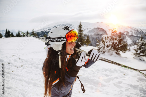 Portrait of beautiful woman with ski and ski suit in winter mountain