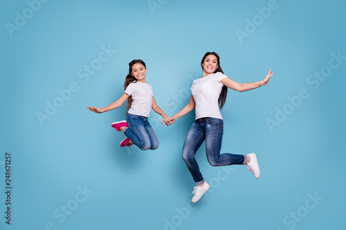 Full length body size view of two nice cute lovely attractive cheerful funny slim sporty people in white t-shirt holding hands having fun rejoicing isolated over blue pastel background