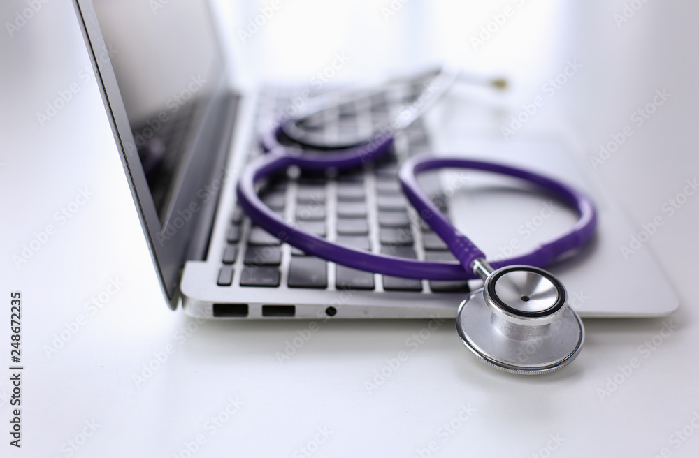 Stethoscope lying on a laptop keyboard in a concept of online m Stethoscope lying on a laptop keyboard in a concept of online m