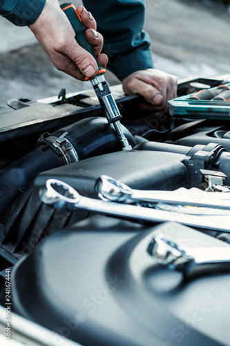 Mechanic repairs car. Car service, engine repair, car repair shop. Place for text.