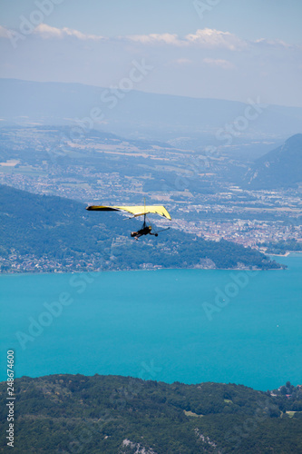 Hang-glider Instructor Flying in Hang-glider with Customer over Annecy Lake Through Mountain Landscape and Cities