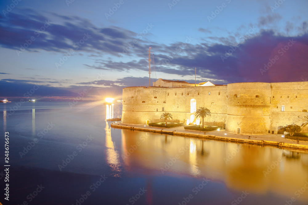 Naklejka premium A beautiful shot of the city of Taranto in south Italy by the main focus areas of the city at late sunset