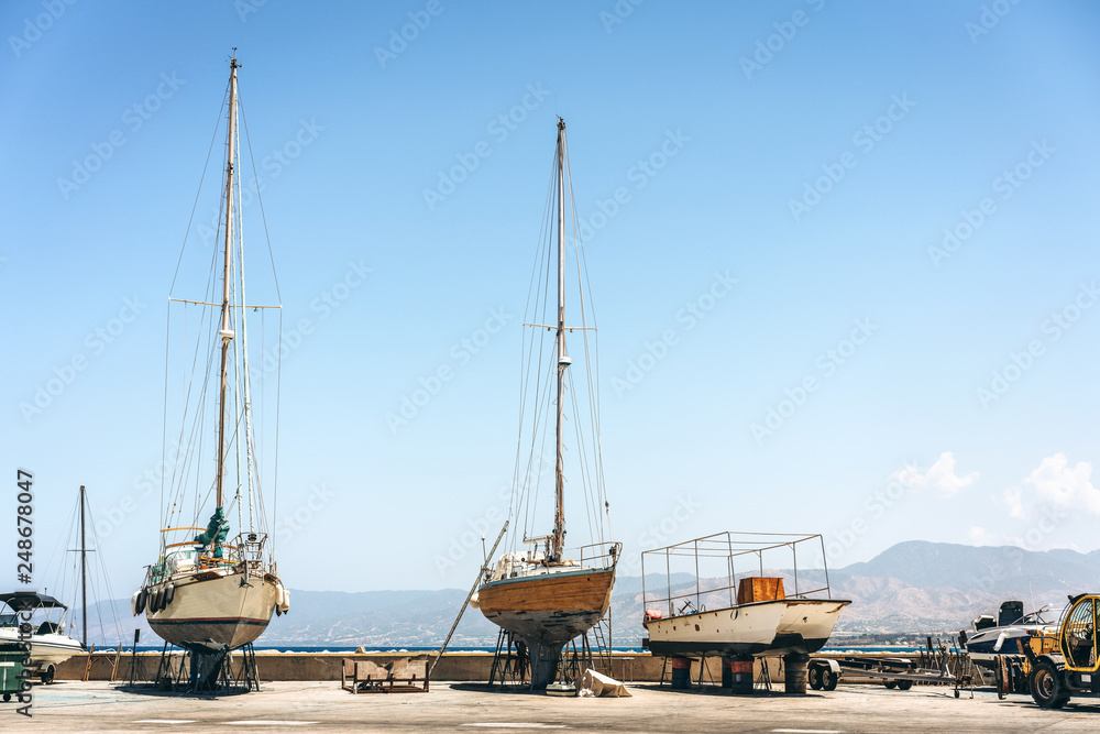 Old fishing boats standing on land near sea waiting for repair.