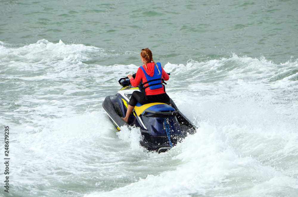 Young blonde woman speeding on a jet ski