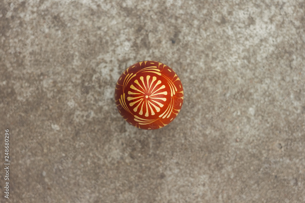 Ukrainian painted easter egg of red color on the background of a gray concrete surface