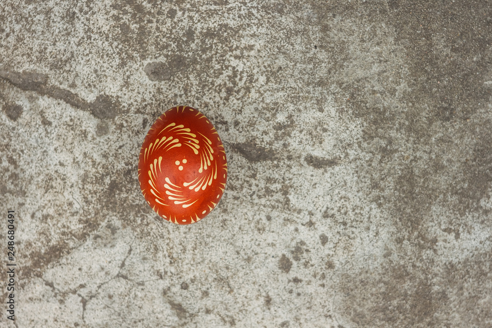 Ukrainian painted easter egg of red color on the background of a gray concrete surface. Copy space